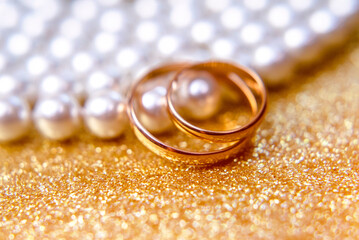 Gold wedding rings lie on a pearl necklace