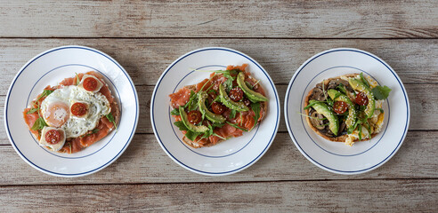 Three healthy avocado toast brunch plates on wood