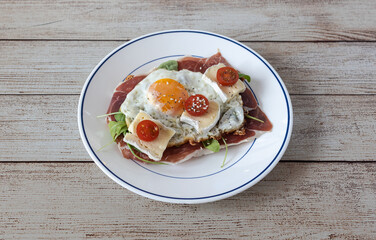 Fried egg open faced sandwich with prosciutto and brie