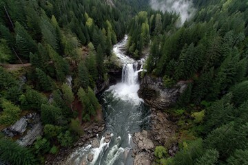 Aerial view of a powerful waterfall flowing through a dense green forest. Highlights nature's raw power and serene beauty, ideal for travel content.