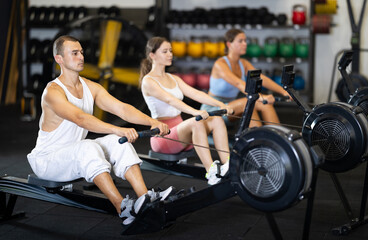 Strong sportsman training at cable row machine in modern crossfit gym