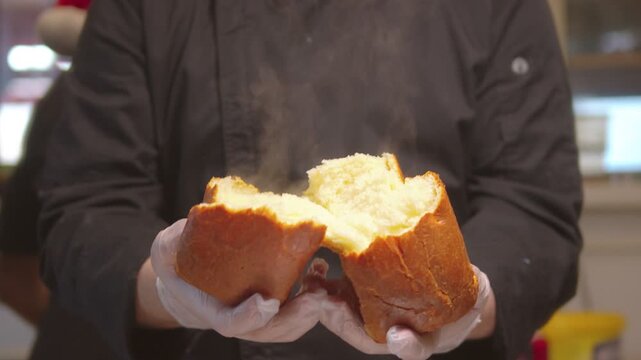 Baker breaking fresh steaming hot bread