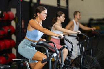 Young woman in sportswear training on exercise bike in gym