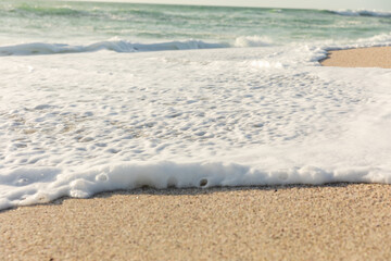 White sea foam with wave splashing on shore at beach on sunny day