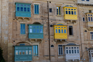Facades of old buildings with windows and colorful balconies on the streets of Valletta, Malta.