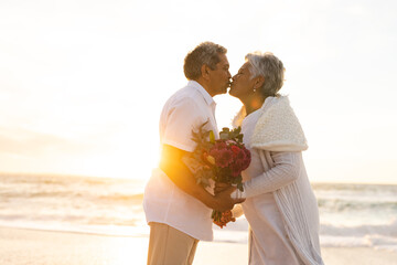 Side view of senior multiracial couple kissing each other during wedding ceremony at beach