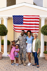 Portrait of smiling african american family with army soldier at entrance against usa flag