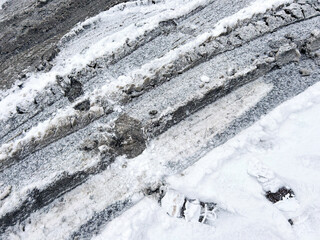 Snow-covered urban road with deep tire tracks and slush, illustrating extreme winter weather conditions, poor traction, and difficult city driving