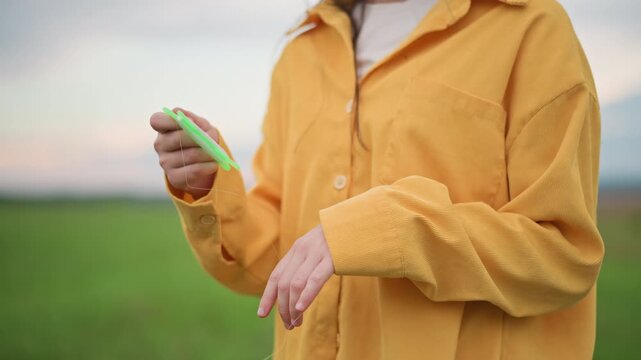 closeup hands adjusting kite winder string, yellow jacket in open meadow at dusk with warm glow, visible tension in line, skillful grip and steady rhythm, cinematic slow motion feel and soft horizon