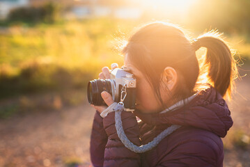 Woman taking photographs with an analog camera at sunset.