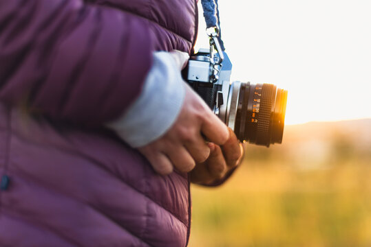 Woman holding her analog camera as the sun sets.