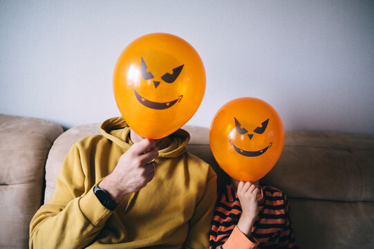 People fooling around with pumpkin balloons for Halloween on couch