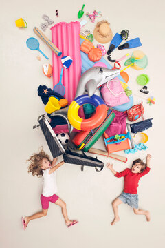 Children with scattered vacation luggage and toys in a studio setting