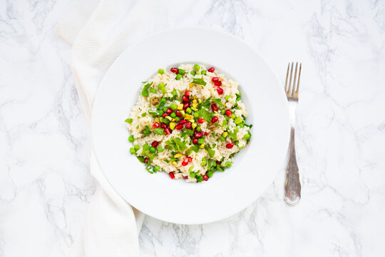Vegetarian risotto with pea, pistachio, and pomegranate seed on marble