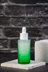 Green glass cosmetic bottle and olive tree branch on green background. Natural organic beauty product background