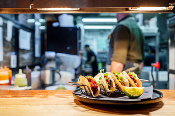 Tacos being plated by chef in professional restaurant kitchen