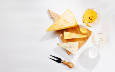 Assorted cheeses and wine glasses on white background