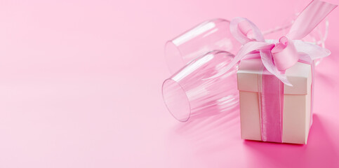 Gift box and wine glasses on pink background