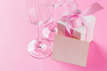 Gift box and wine glasses on pink background
