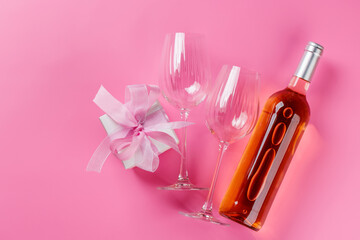 Gift box and wine glasses on pink background