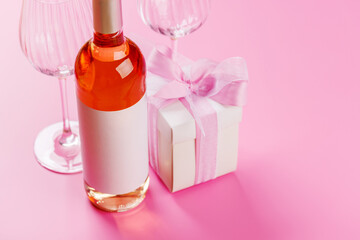 Gift box and wine glasses on pink background