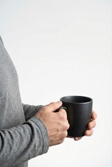 Person holding a black mug against a white background