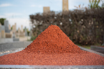 霊園の墓前に盛られた赤玉土の盛り土とボケた背景（墓地メンテナンス・化粧砂・テクスチャ素材）