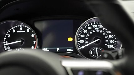 A detailed closeup view of a modern cars dashboard with the speedometer tachometer and a digital display showing an illuminated yellow warning light indicating a potential vehicle malfunction or serv. - Powered by Adobe