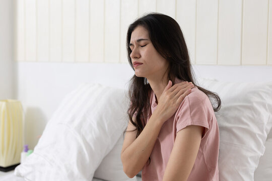 Women holding shoulder in pain, possibly due to muscle strain, frozen shoulder, postural tension, ideal for physical therapy, ergonomic health content.