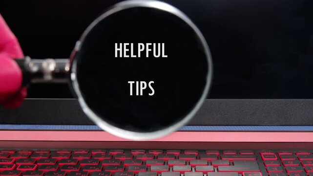 A magnifying glass is used to reveal the text Helpful Tips. The glass moves over a dark surface and a luminous keyboard, bringing the message into focus
