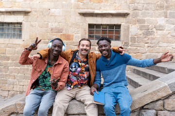 Three diverse male friends laughing and posing together on city vacation