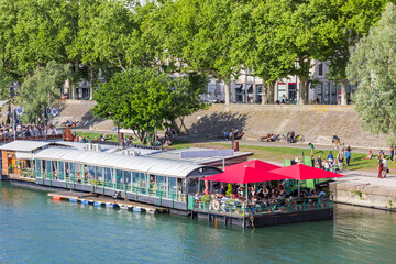 People eating and drinking at a floating cafe in the Rhone river in Lyon, France