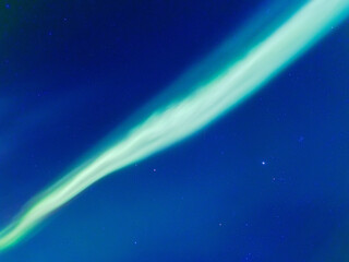 Spectacular Aurora Borealis dancing across the starry night sky. Vibrant green northern lights phenomenon over Scandinavia, glowing celestial light show, deep space stars and cosmos. High resolution.