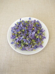 A plate with dried wild mallow flowers for making herbal tea on a table