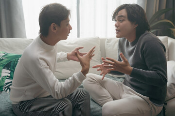 Asian gay couple having Serious emotional talk ,heated discussion in living room at home