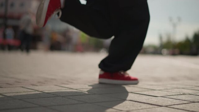 red sneakers tapping on sunlit pavement. street dancer performing dynamic footwork in busy city square, baggy pants, lowangle closeup, motion blur, energetic rhythm, subtle shadow, urban crowd