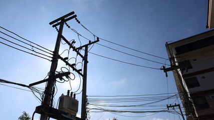 Silhouette of a transformer on a pole. 3 phase power transformer with many cables on pole structure...