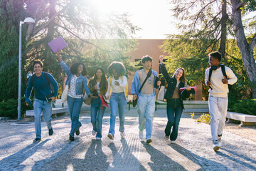 Naklejka premium Multiracial young adult students smiling, laughing, and running on a sunny university campus path, expressing freedom and joy