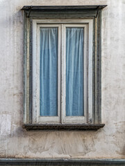 Minimalist architectural detail of a rustic window on a textured, aged wall in the heart of Naples, Italy.