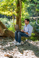 White collar worker is using ragged laptop while vacation at forest.