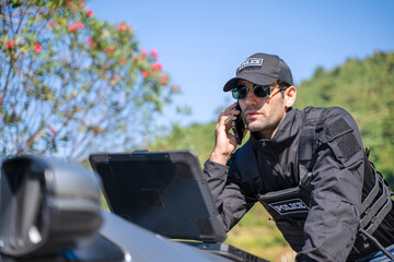 The police officer is working with rugged laptop at the dam.