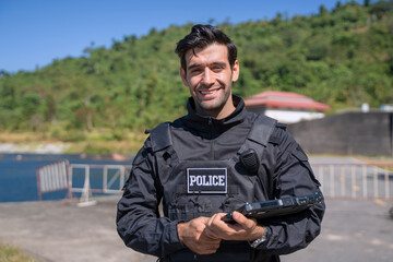 The police officer is working with rugged laptop at the dam.