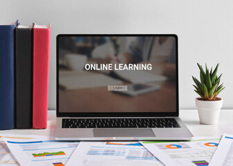 Laptop displaying online learning website on white desk with documents, books and plant