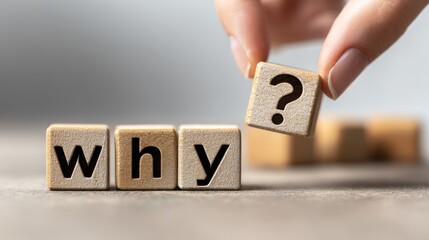The wooden blocks spelling why with a question mark cube held by hand