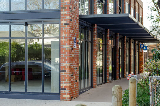 An empty corner retail unit with glass frontage at street level along a pedestrian walkway. Unoccupied commercial shop space suitable for retail or service use at an urban corner location.