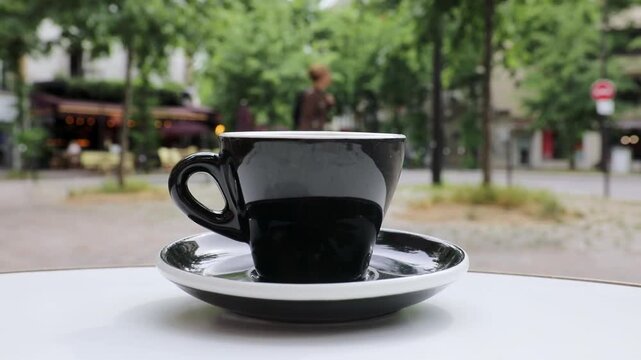 Cup of fresh hot coffee on the table of an outdoor cafe in Paris, France.
