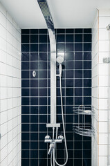 A modern shower with a sleek chrome showerhead and tiled walls. The design emphasizes cleanliness and hygiene in a contemporary bathroom setting.