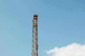 yellow construction crane boom, blue sky with small clouds, industrial lifting equipment used in building and engineering projects, construction, industry, development