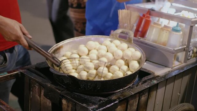 Selective focus of a street food vendor friying Tahu bulat or deep fried rounded tofu. Popular snack in Indonesia made from soy curd
