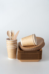 Eco-friendly disposable tableware with paper cups, wooden cutlery, kraft plates, symbolizing sustainable lifestyle, zero waste, and biodegradable packaging.